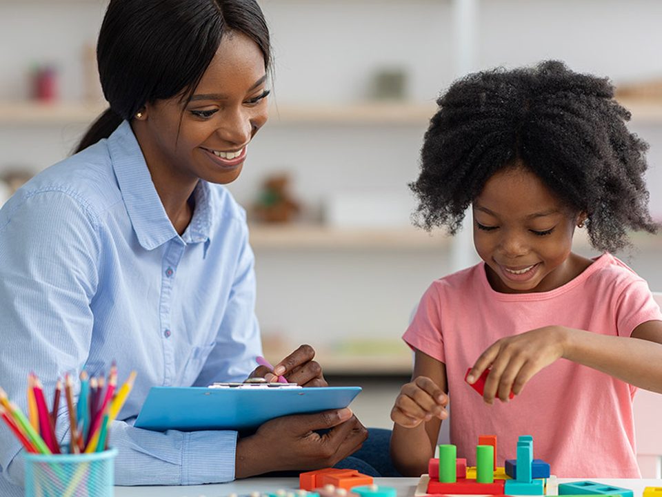 A clinician working with a young girl at a table
